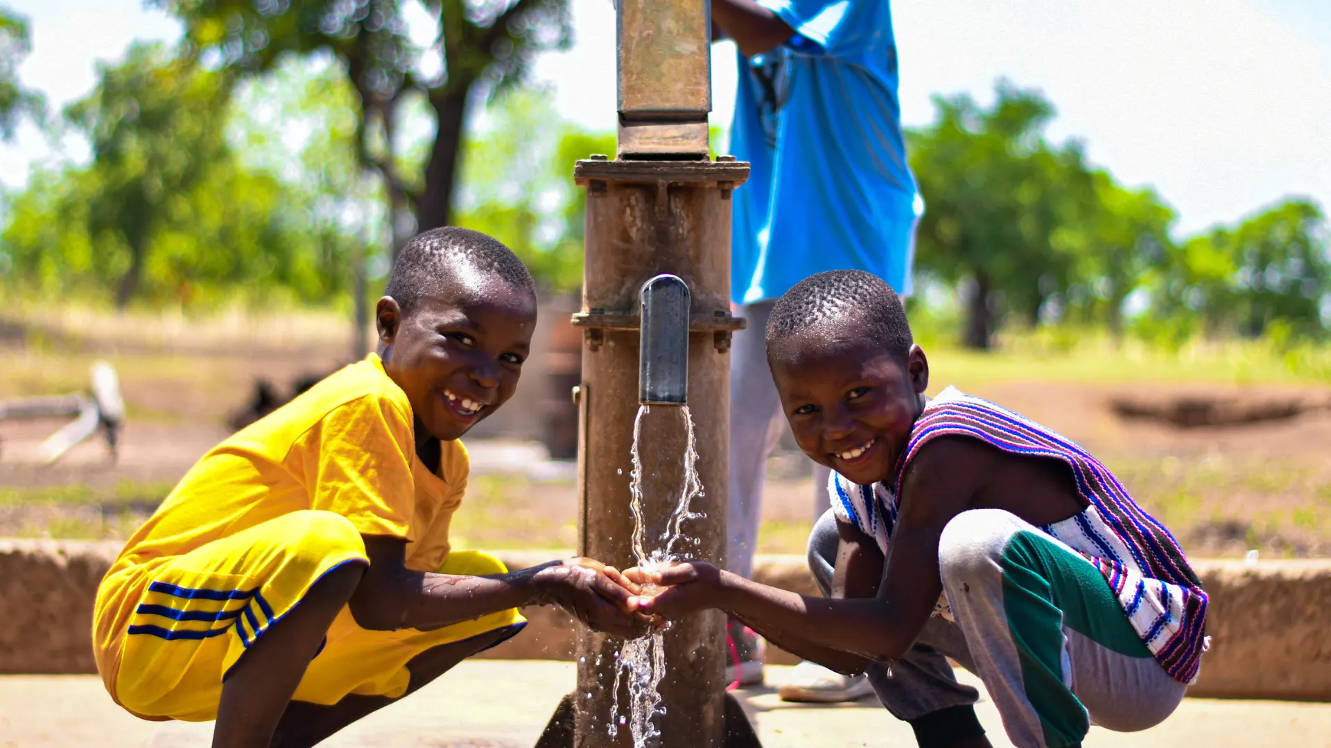 Kinderen vangen vers water bij een handpomp