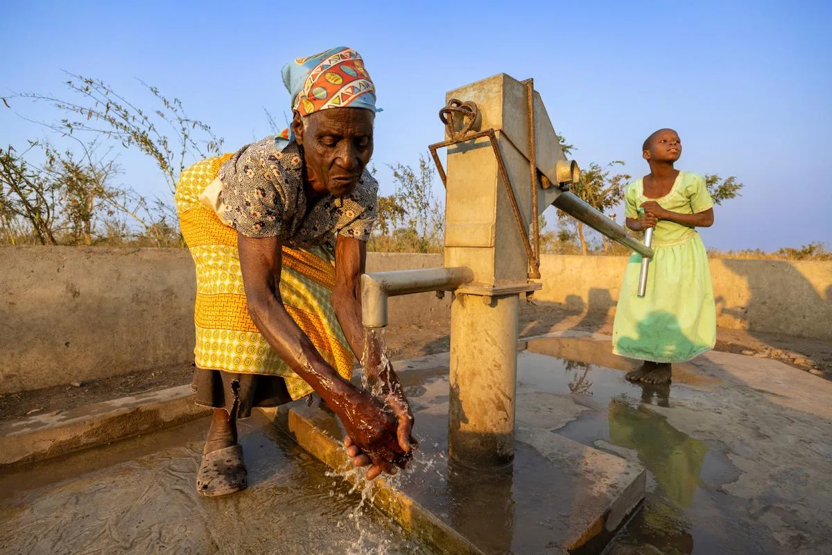 Vrouw pompt water bij een dorpsbron